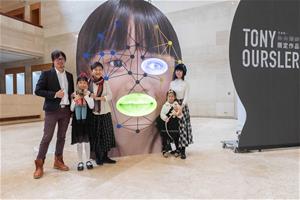 參與徵臉企劃入選的徐筱樂同學(左二)一家人與高美館李玉玲館長(左三)共同在藝術家湯尼．奧斯勒的全新作品前短暫取下口罩共同合影留念。