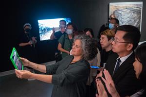 2_藝術家珍妮佛．貝奇沃(前排左)為高市府秘書長郭添貴(前排中)與會貴賓介紹《人類世》AR體驗。