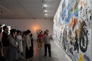 藝術家李明則為開幕活動與會者導覽介紹作品〈走自己路的〉。